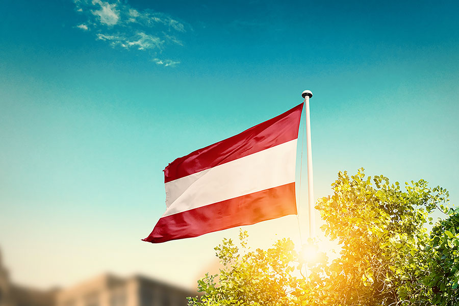 The national flag of Austria against the background of the blue sky, symbolizing the beauty of the country
